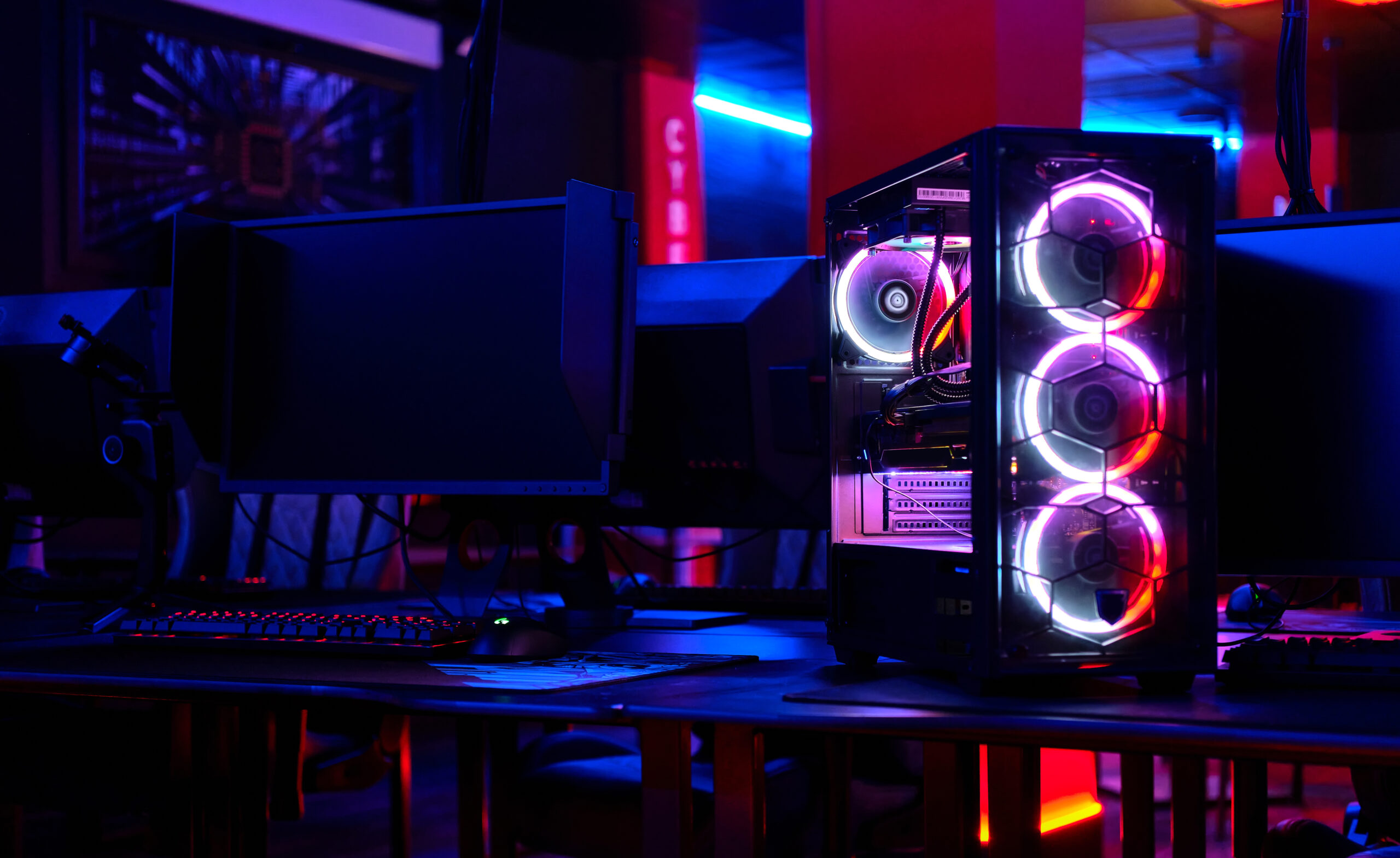 Top-end system unit for gaming computer close up. Inside of illuminated cybercafe. Concept of modern tech, fun, esport, online video games internet cafe